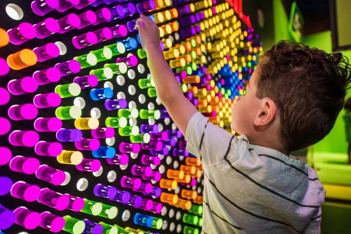 A young guest plugs colored pegs into a Lite-Brite-style interactive mural in the <em>Dream Tomorrow Today</em> exhibit.