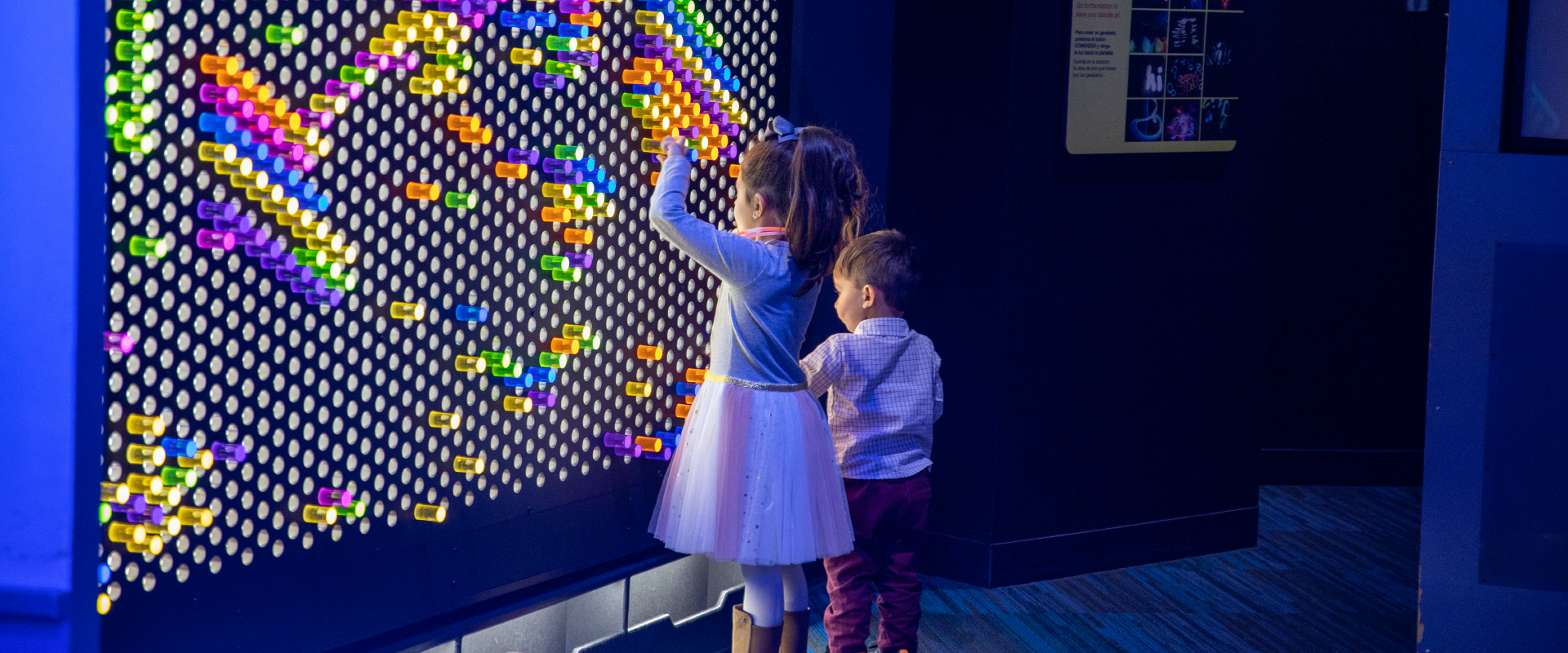 Children plug colored pegs into a Lite-Brite-style interactive mural in the <em>Dream Tomorrow Today</em> exhibit.